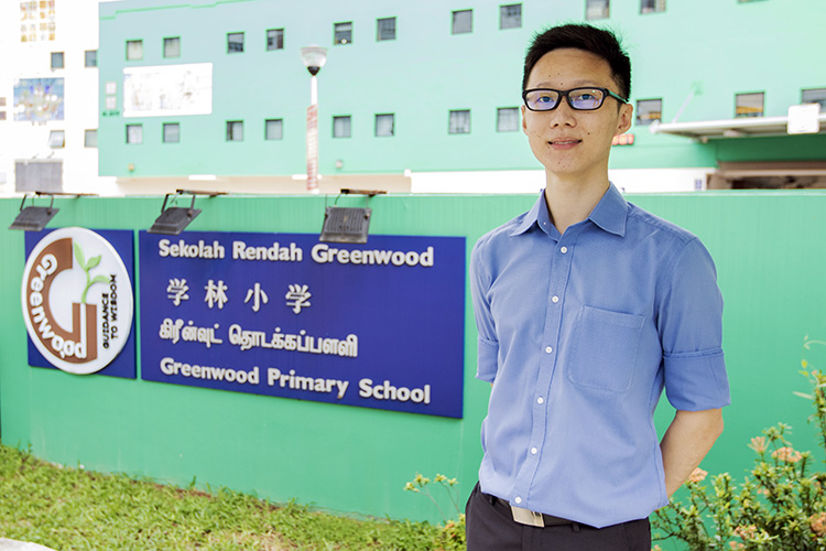 mr daniel ng standing infront of school entrance photo