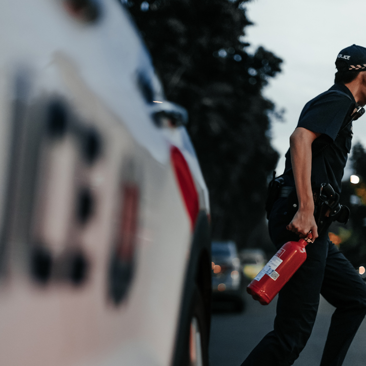 police officer holding fire extinguisher and running