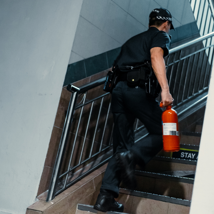 police officer holding fire extinguisher and rushing up the flight of stairs