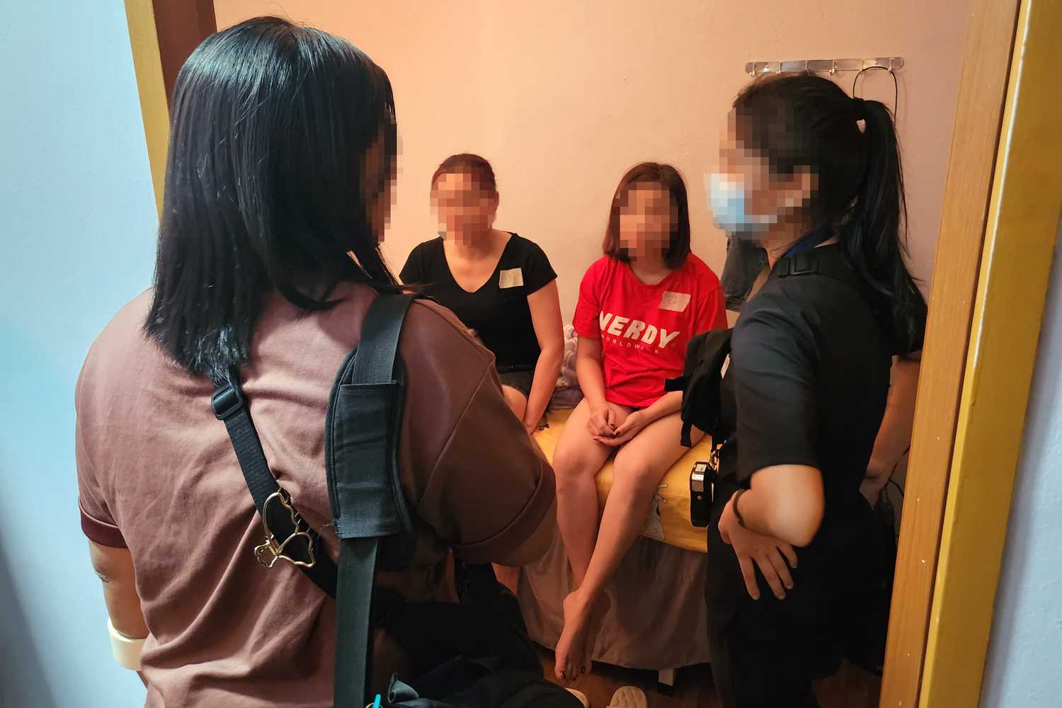 female police officers interviewing suspects who are seated on a bed 