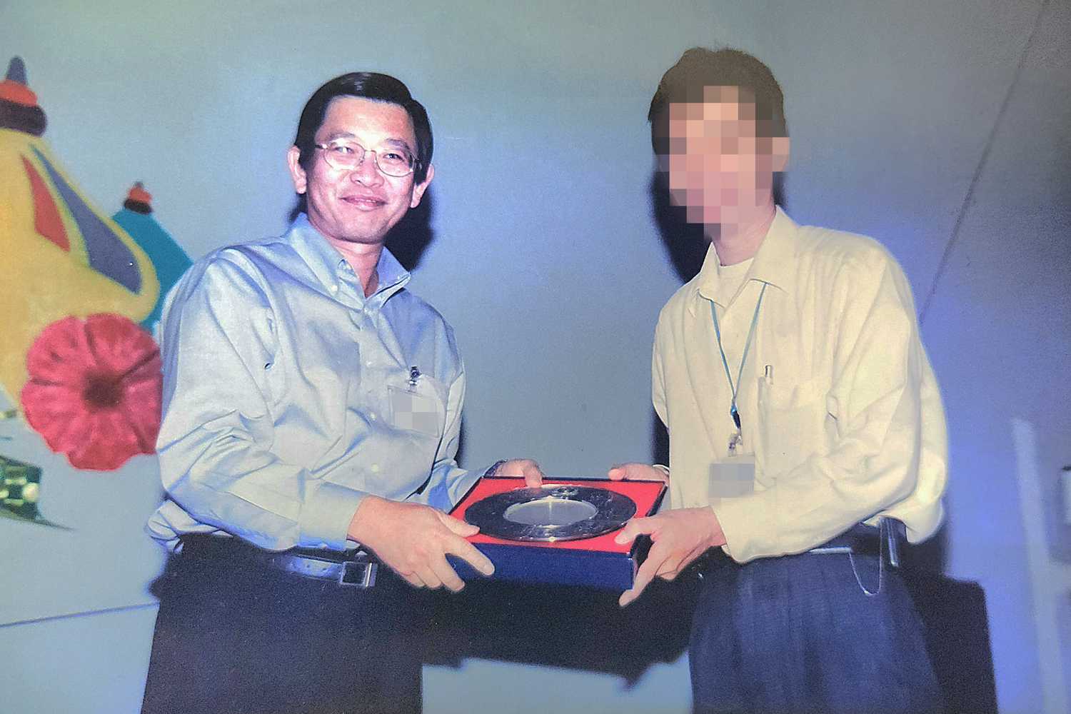 an aged photo of an award ceremony where a male officer in white smart attire is receiving an award on stage