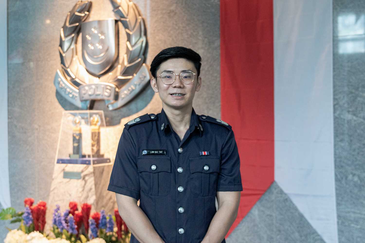 SSSgt Low Kai Tat standing in front of the Singapore crest