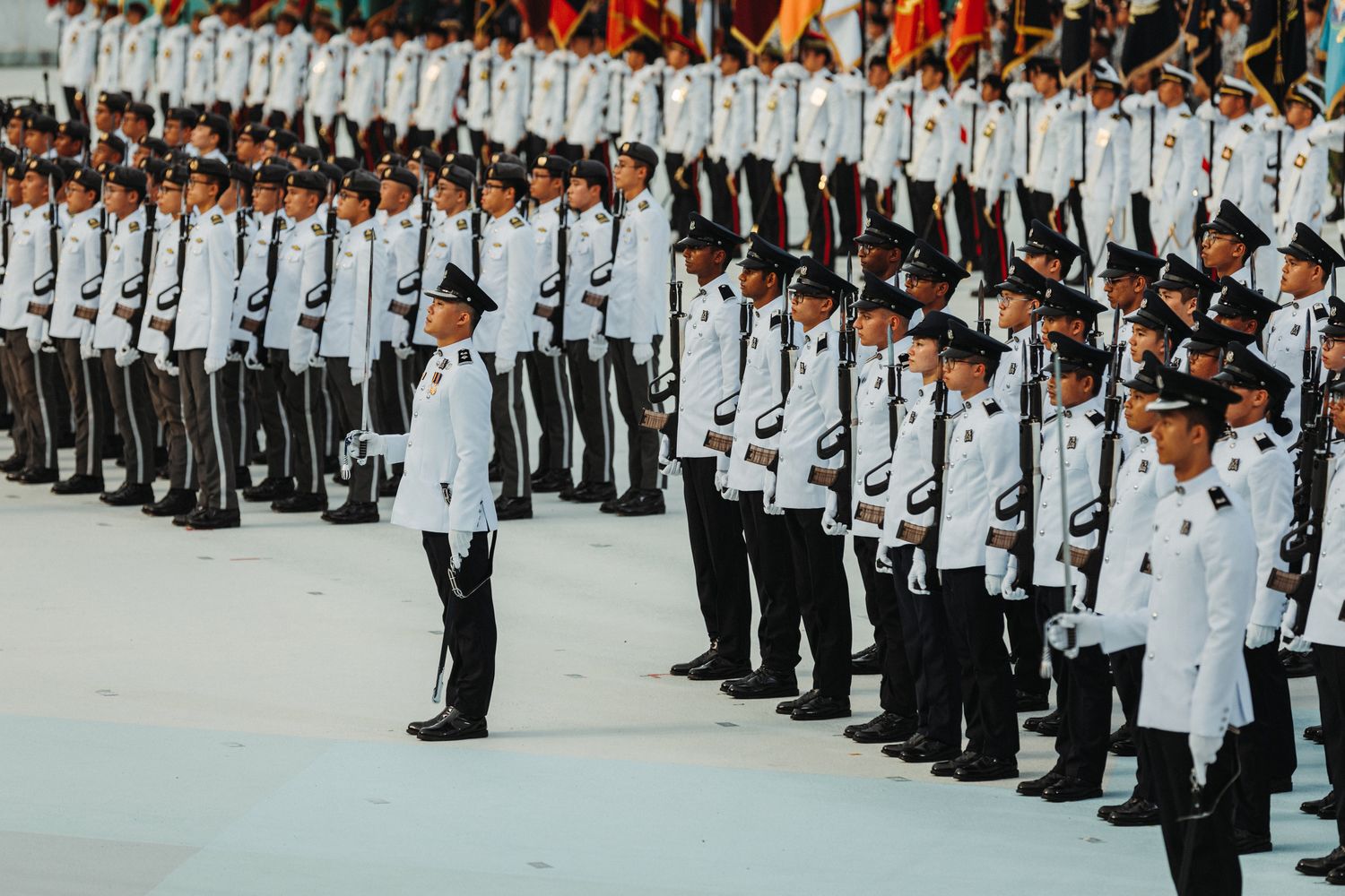 a photo of many officers wearing white Guard of Honour ceremonial attire standing in salute facing the left