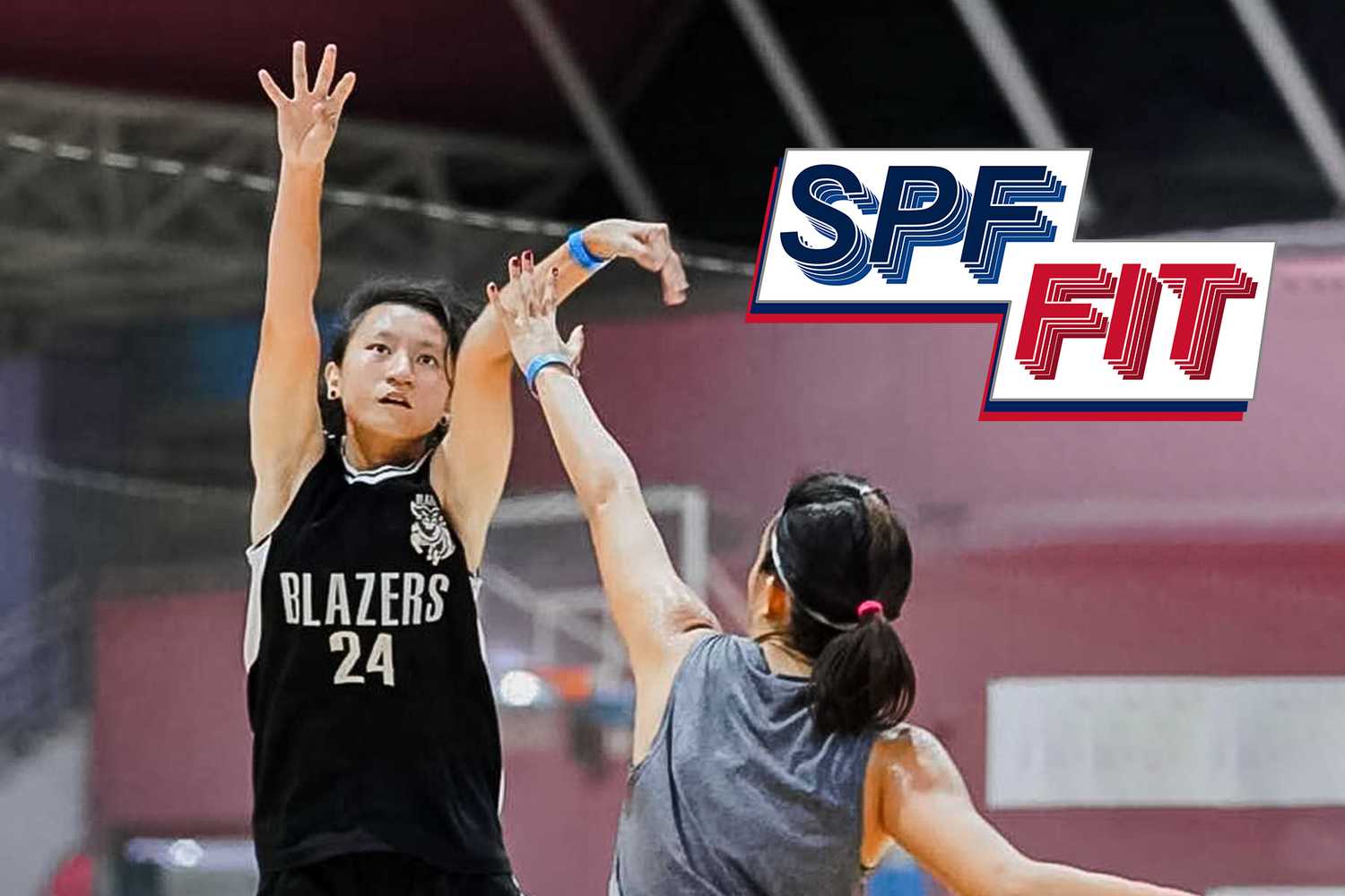 Sergeant Ivie Lim is playing basketball in this photograph, and seems to have just thrown a shot into the hoop from her hand gesture, there is another woman with her back faced to the camera trying to block her. The words "SPF Fit" is included in the photograph.