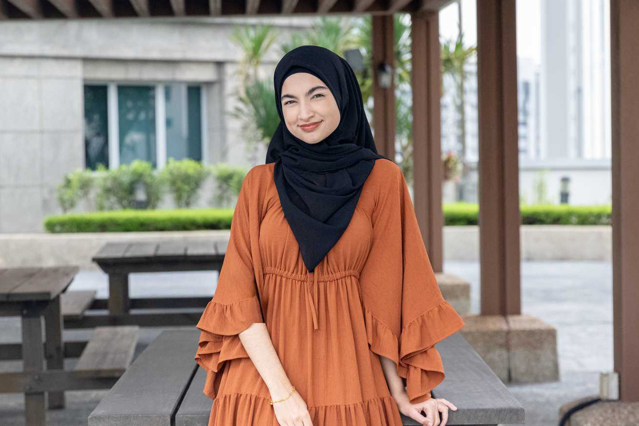 Female officer posing, wearing a a tan blouse and black headscarf