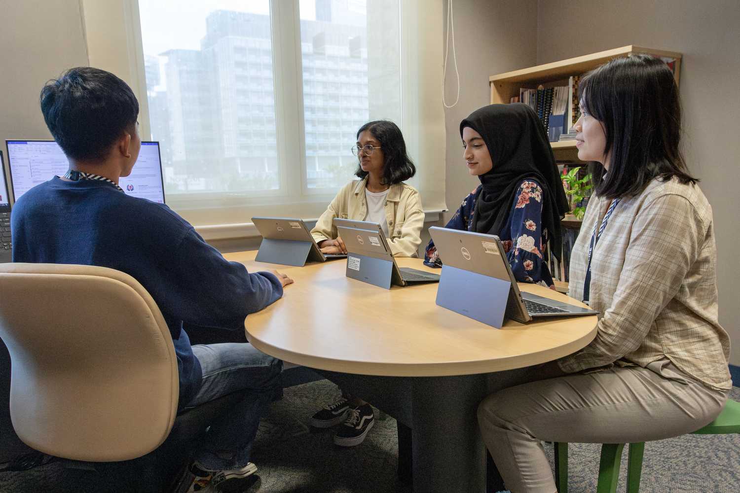 four officers having a discussing at an office table, with light shining through a window behind them