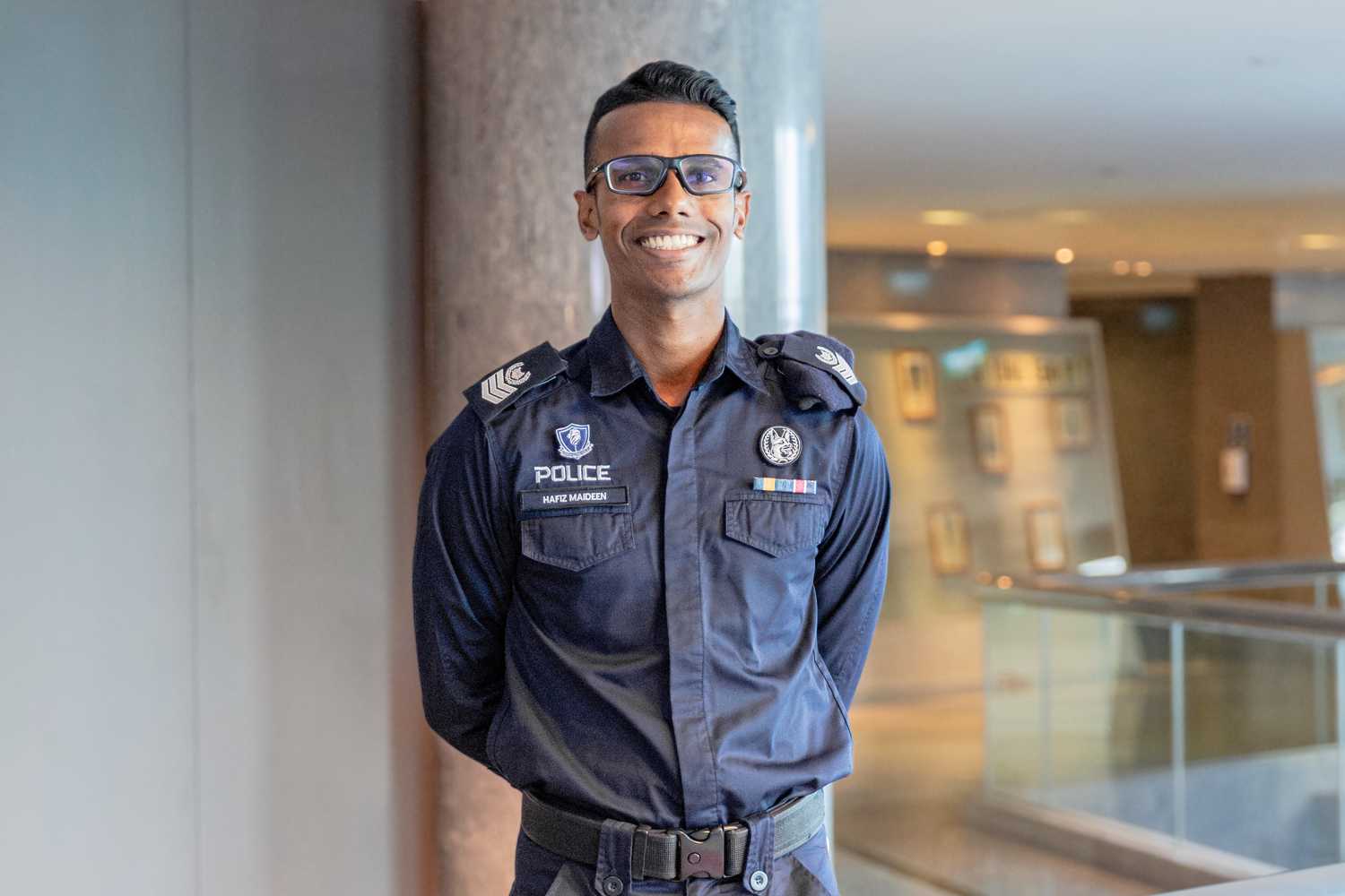 SSSgt Hafiz, with his hands behind his back, looking proudly at the camera and smiling in uniform