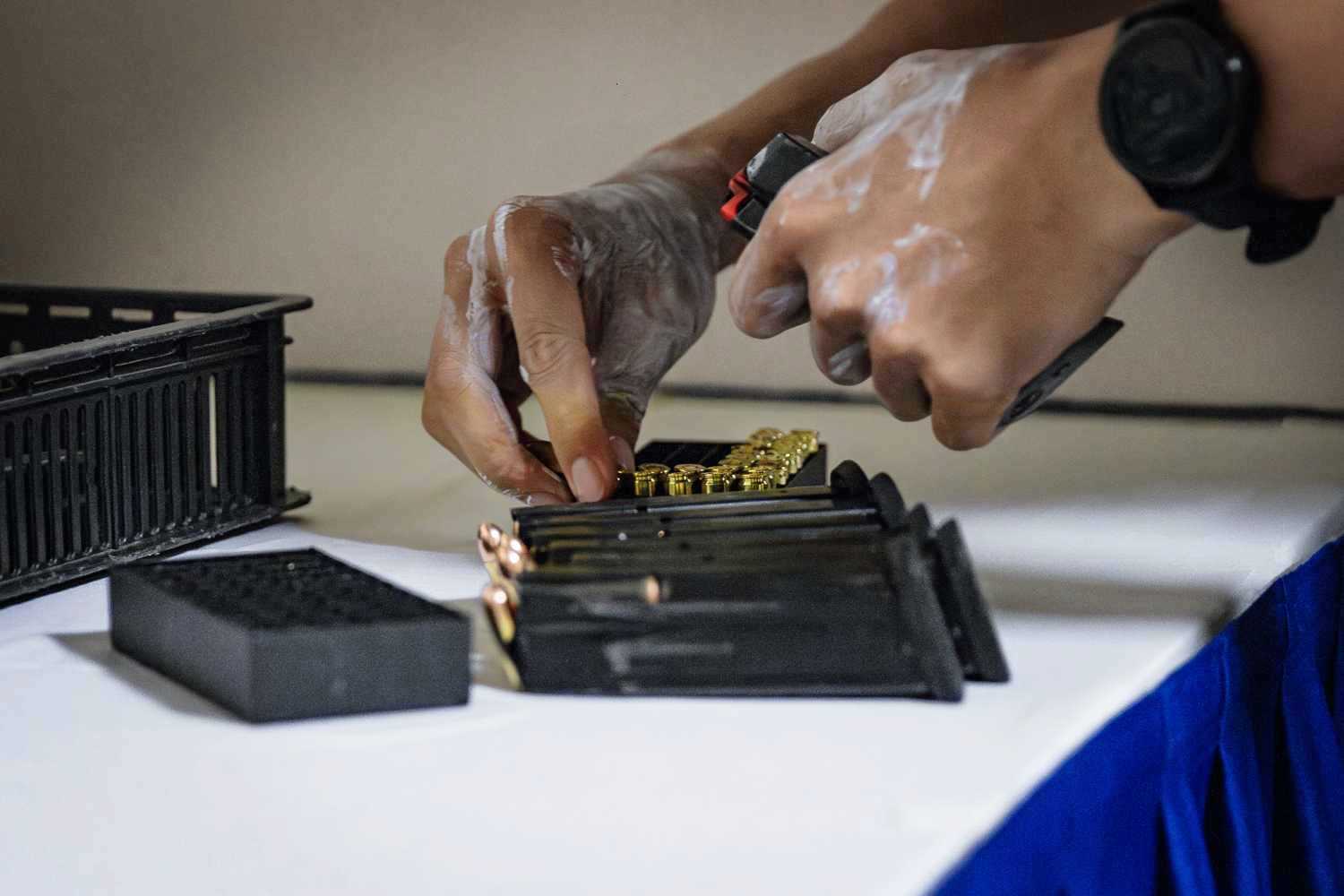 an officer loading gold coloured bullets into a pistol magazine round