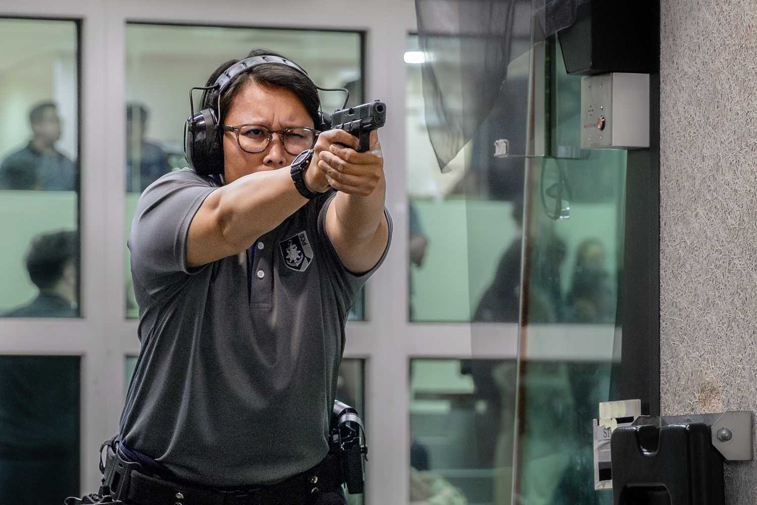 officer in shoulder stance firing the gun. she is wearing ear protection gear