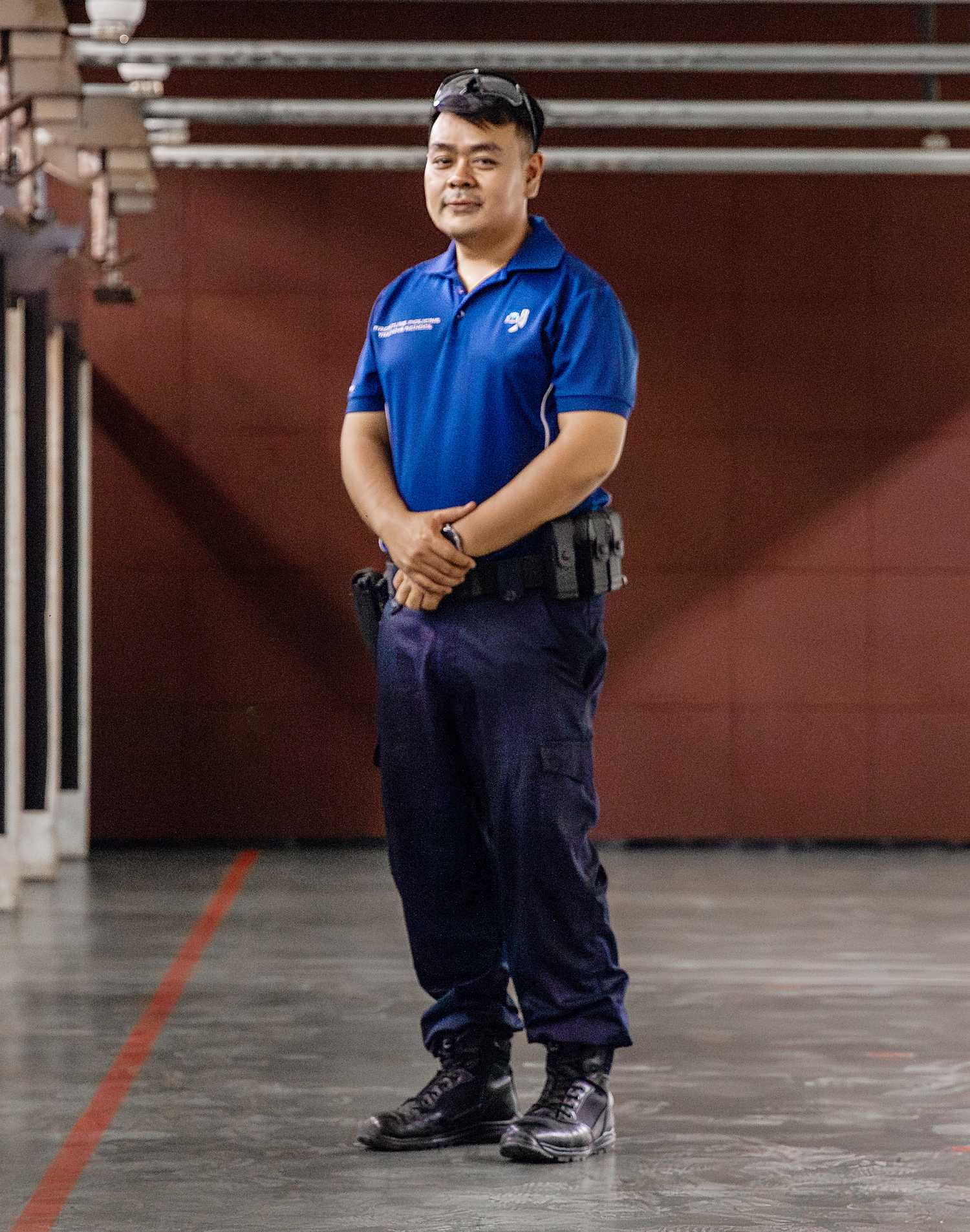 officer in range wearing blue and posing for the camera, with dark background in the back