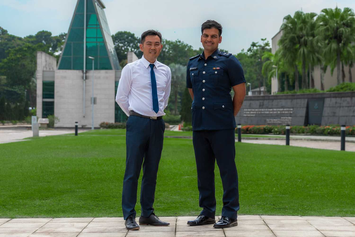 DSP Mohamad Faizal and Mr Seah Chee Wei are standing side by side and looking at the camera proudly in a patch of grass at the Home Team Academy.