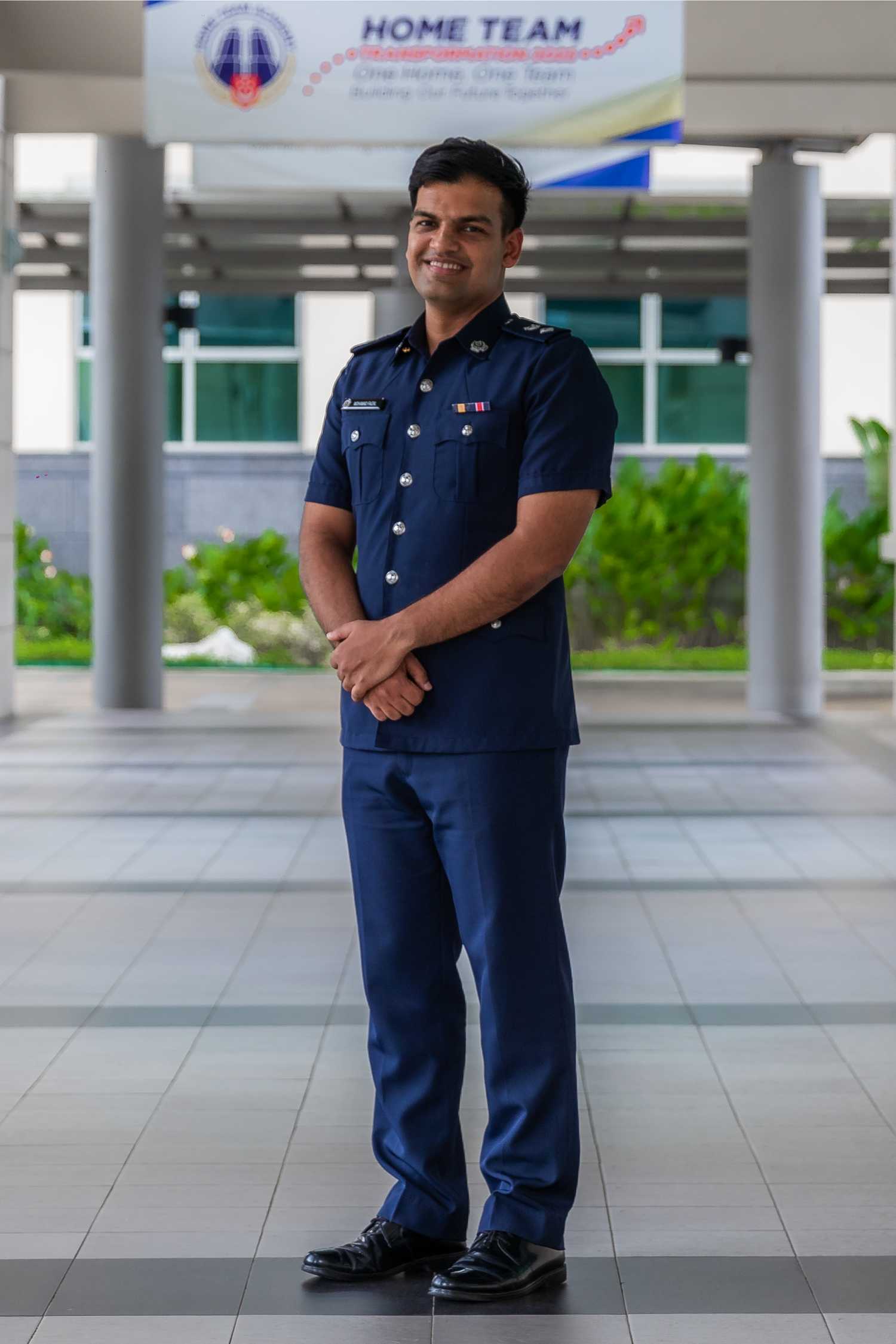 DSP Mohamad Faizal is looking proudly and smiling at the camera in a profile shot. He is in uniform and his hands are folded neatly in front of him.