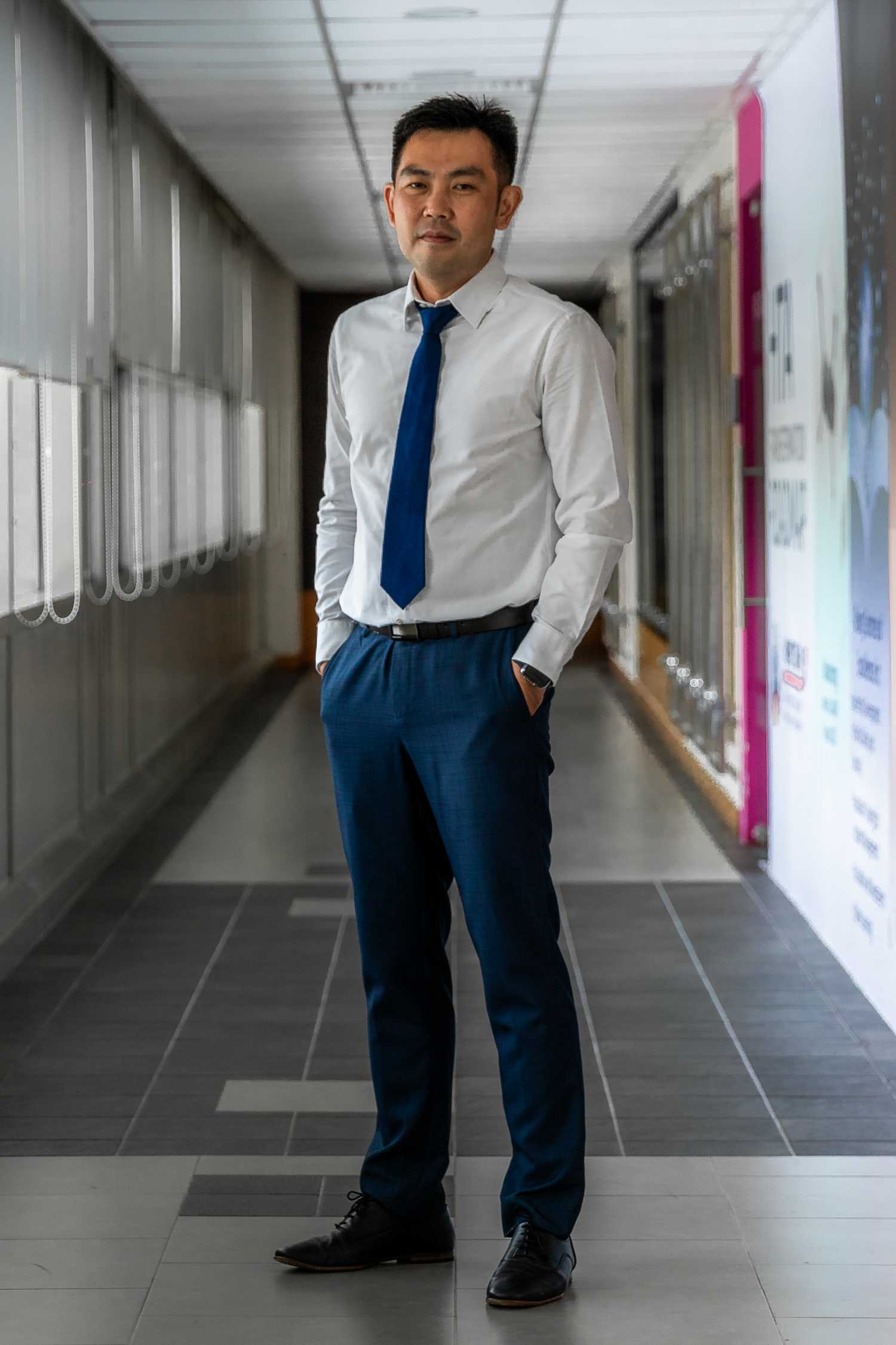 Mr Seah Chee Wei is standing and looking proudly at the camera in a profile shot. He is dressed in formal wear, in a suit and tie.