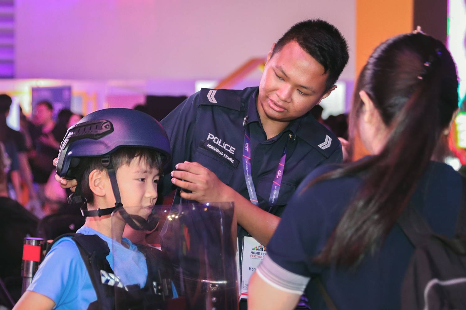 an officer donning a kevlar helmet onto a kid for a photographic opportunity
