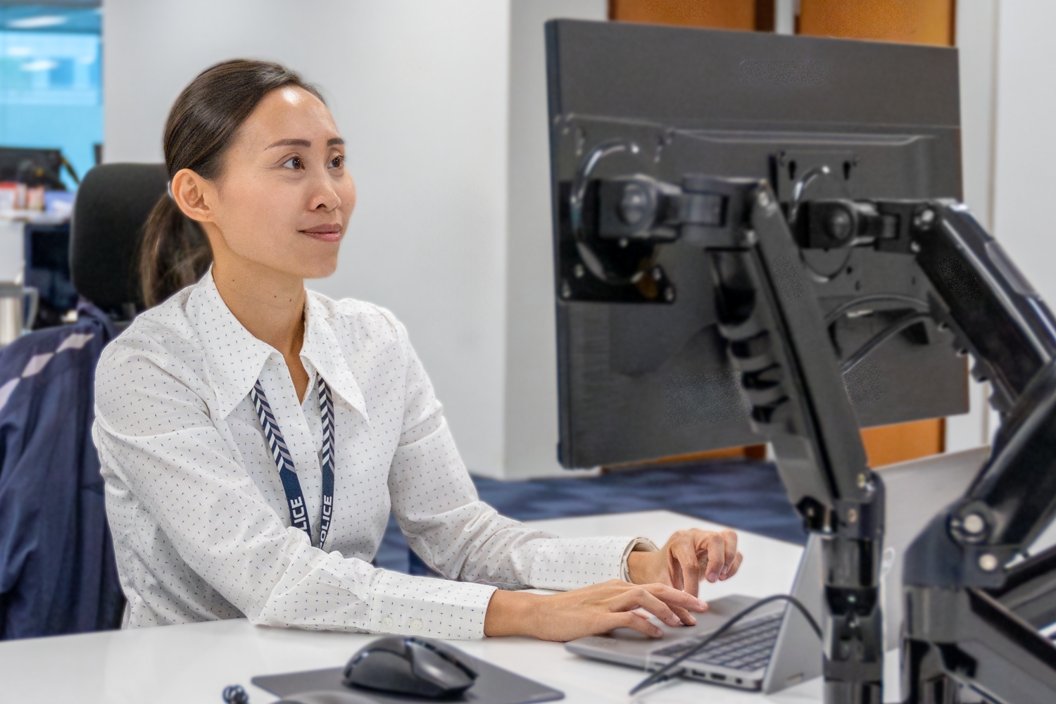 A profile photo of DSP Clara Wong sitting at a desk, looking at a computer monitor. Her hands are extended on a keyboard, and she has a slight smile on her face.