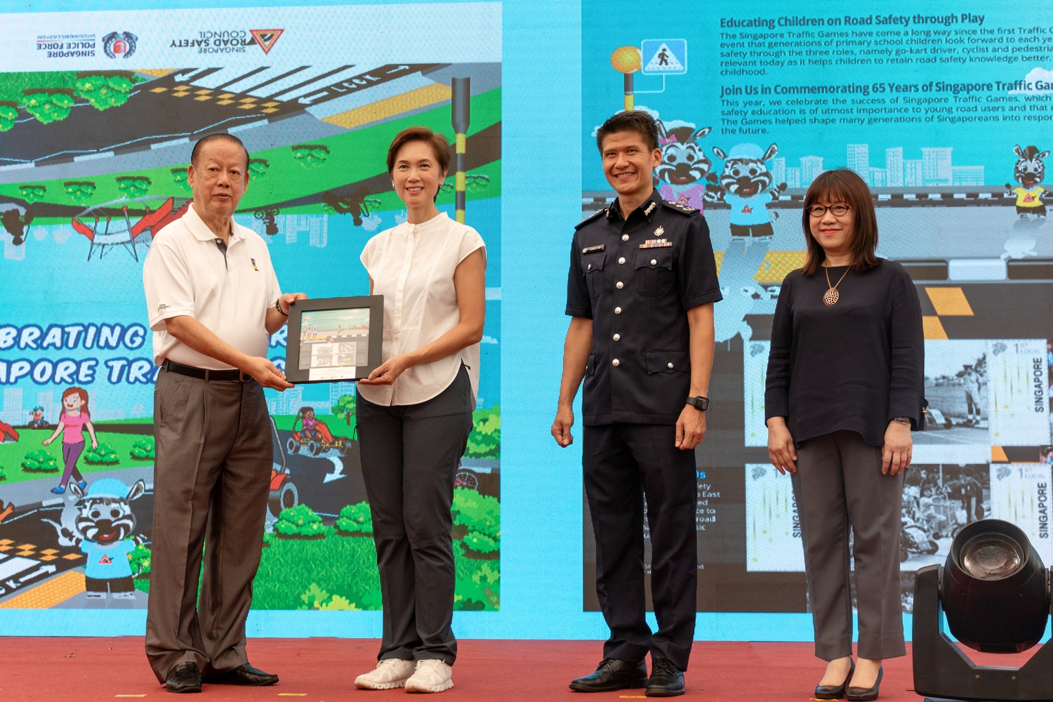 Mr Bernard Tay, Chairman of the SRSC, presents the unique Stamp Presentation Pack to Mrs Josephine Teo. Senior Assistant Commissioner of Police Daniel Tan, Commander of Traffic Police, and Mdm Susan Wang, Superintendent East 2, Schools Division, MOE, were on stage to see the exchange as well. 