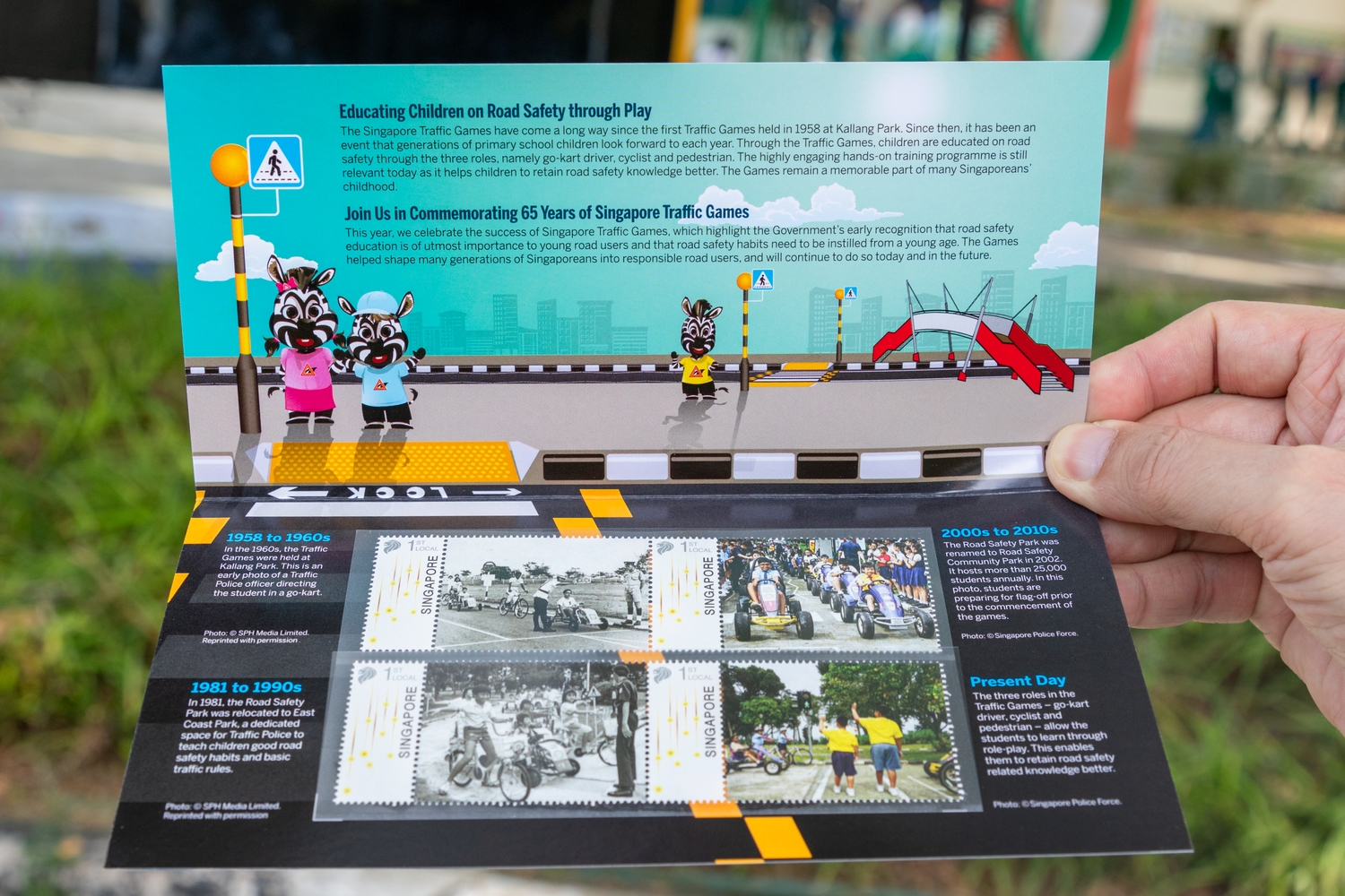 A close-up shot of the commemorative Stamp Presentation Pack, which showcases four generations of students participating in the Singapore Traffic Games.