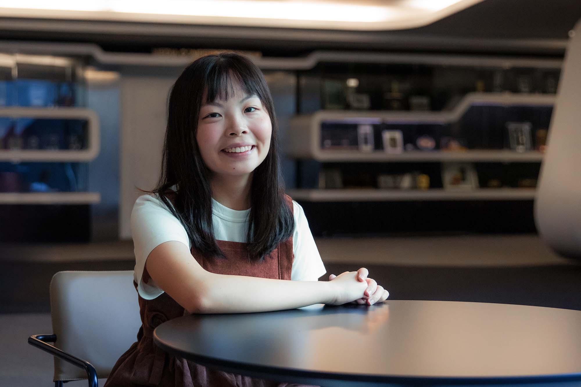 A portrait shot of Amanda Wong. She is sitting on a chair with her hands neatly placed on a table.