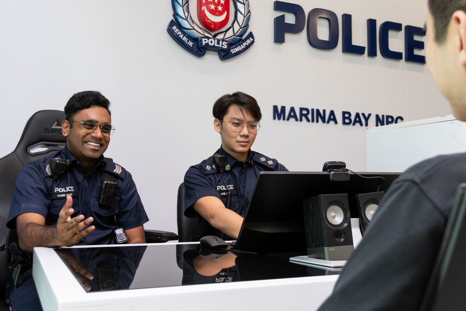 two officers at the front counter of Marina Bay NPC talking to a member of the public