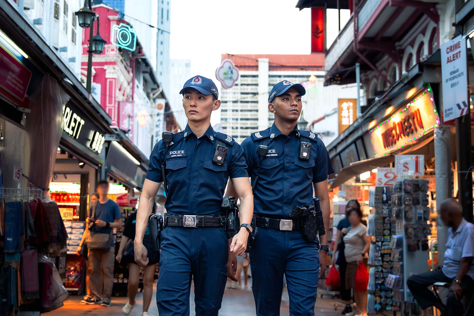 two officers walking towards the 6pm direction, between shophouses in chinatown.