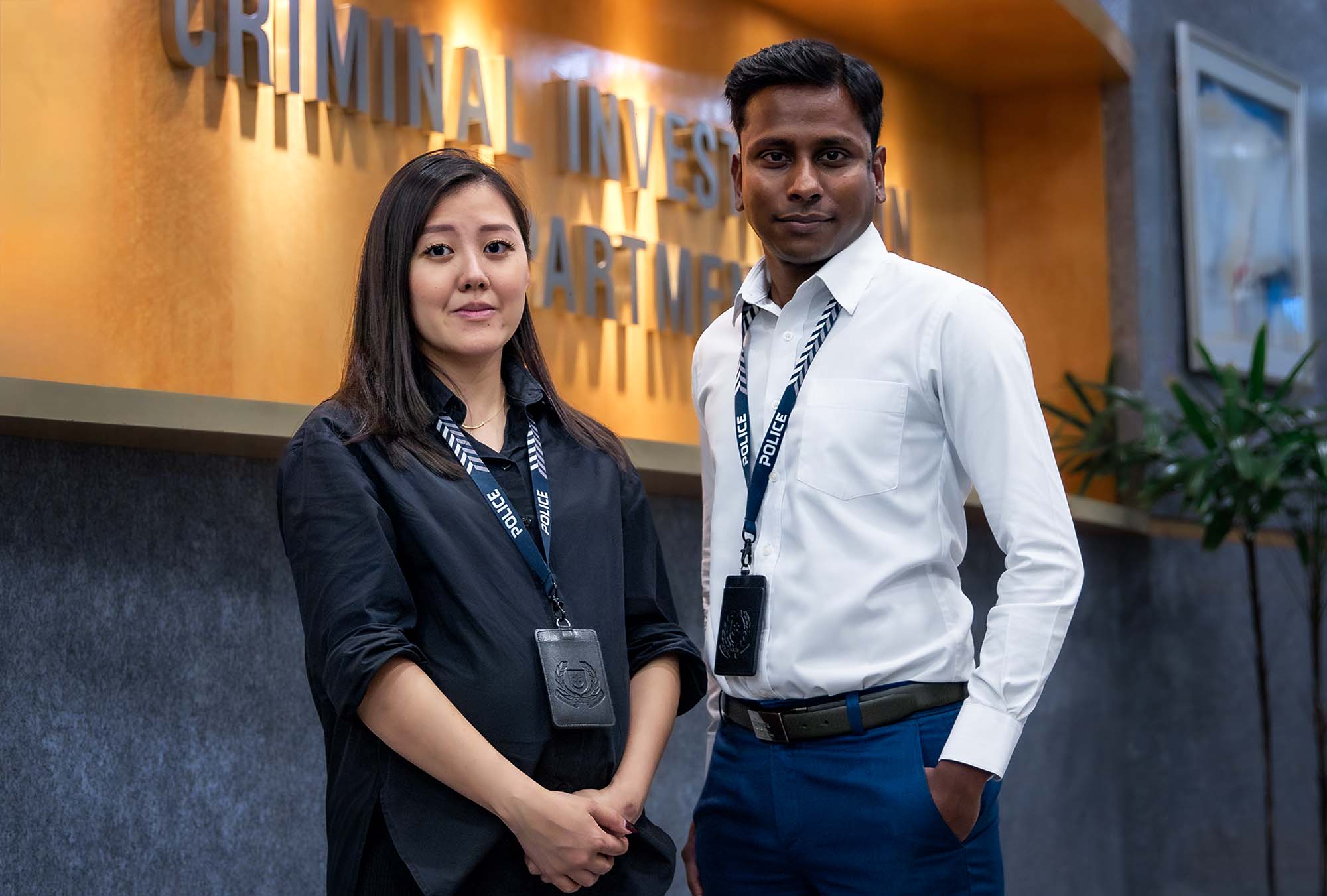 Photo of two officers standing infront of a signage that says CID