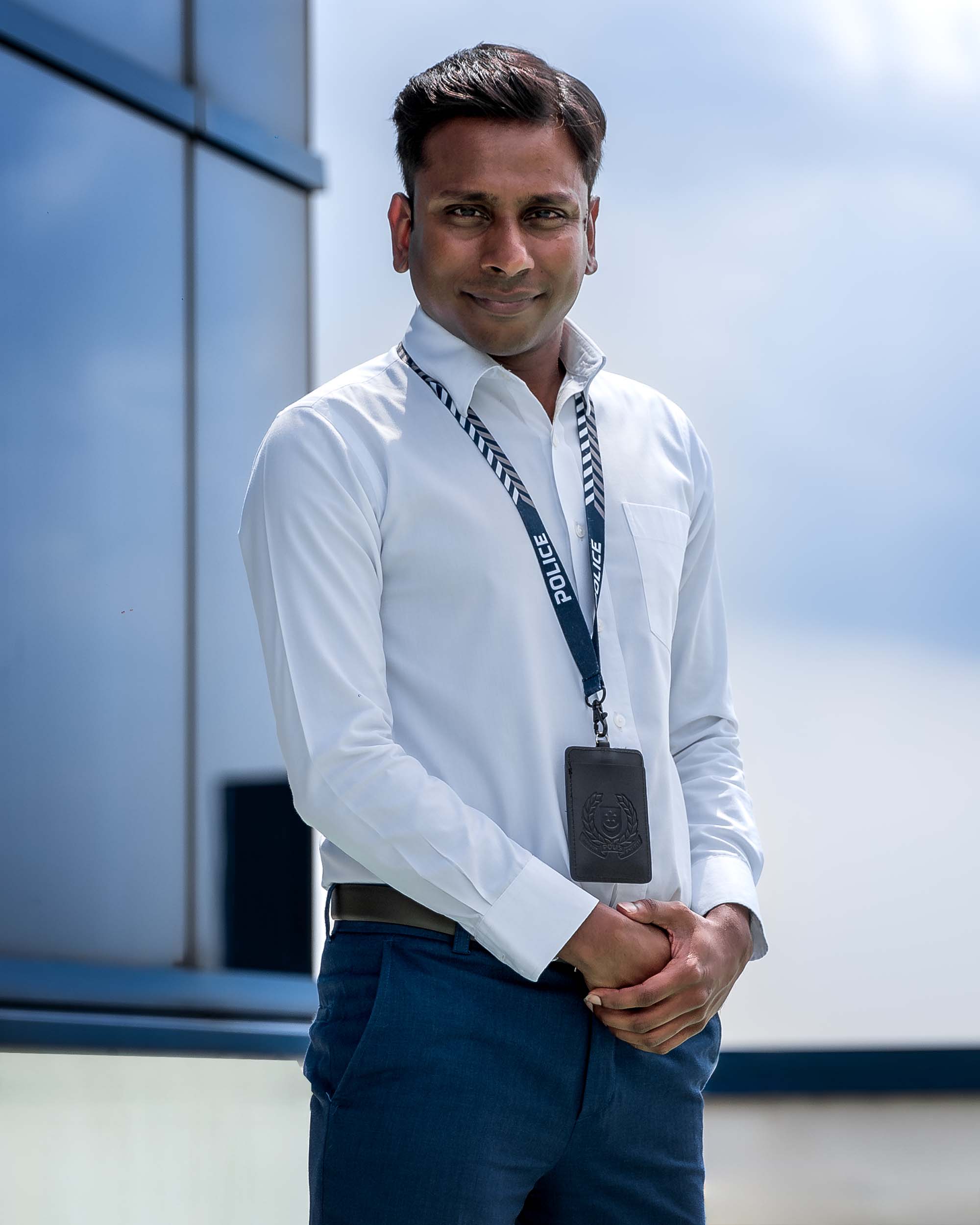 male officer in white formal attire standing at a rooftop and posing for photo with his arms clasped infront of him