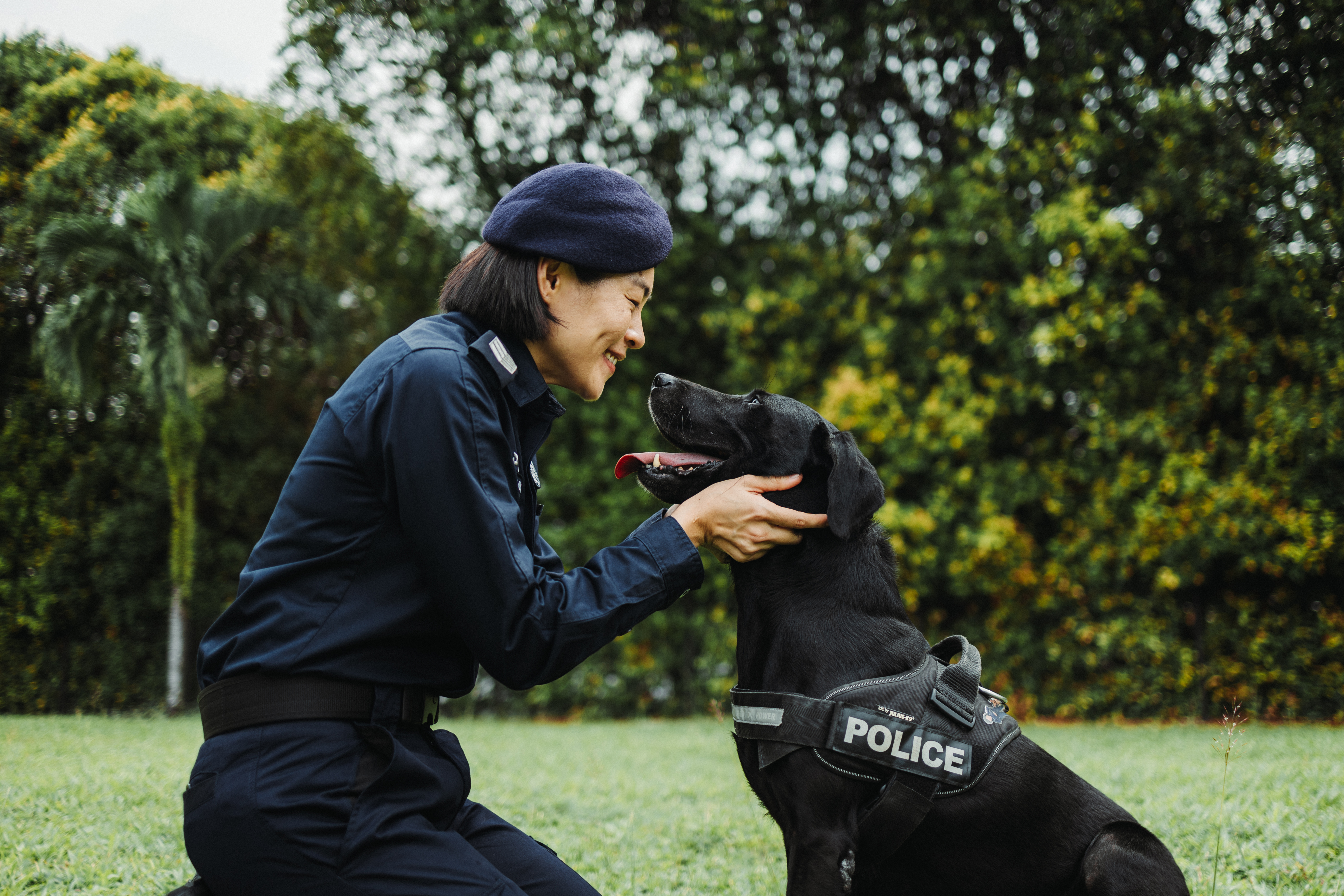 Police Officer holding onto dog's cheeks and looking at him, smiling