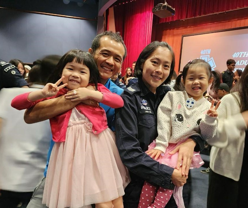 father carrying daughter and mother carrying another daughter. Mother is in police uniform.