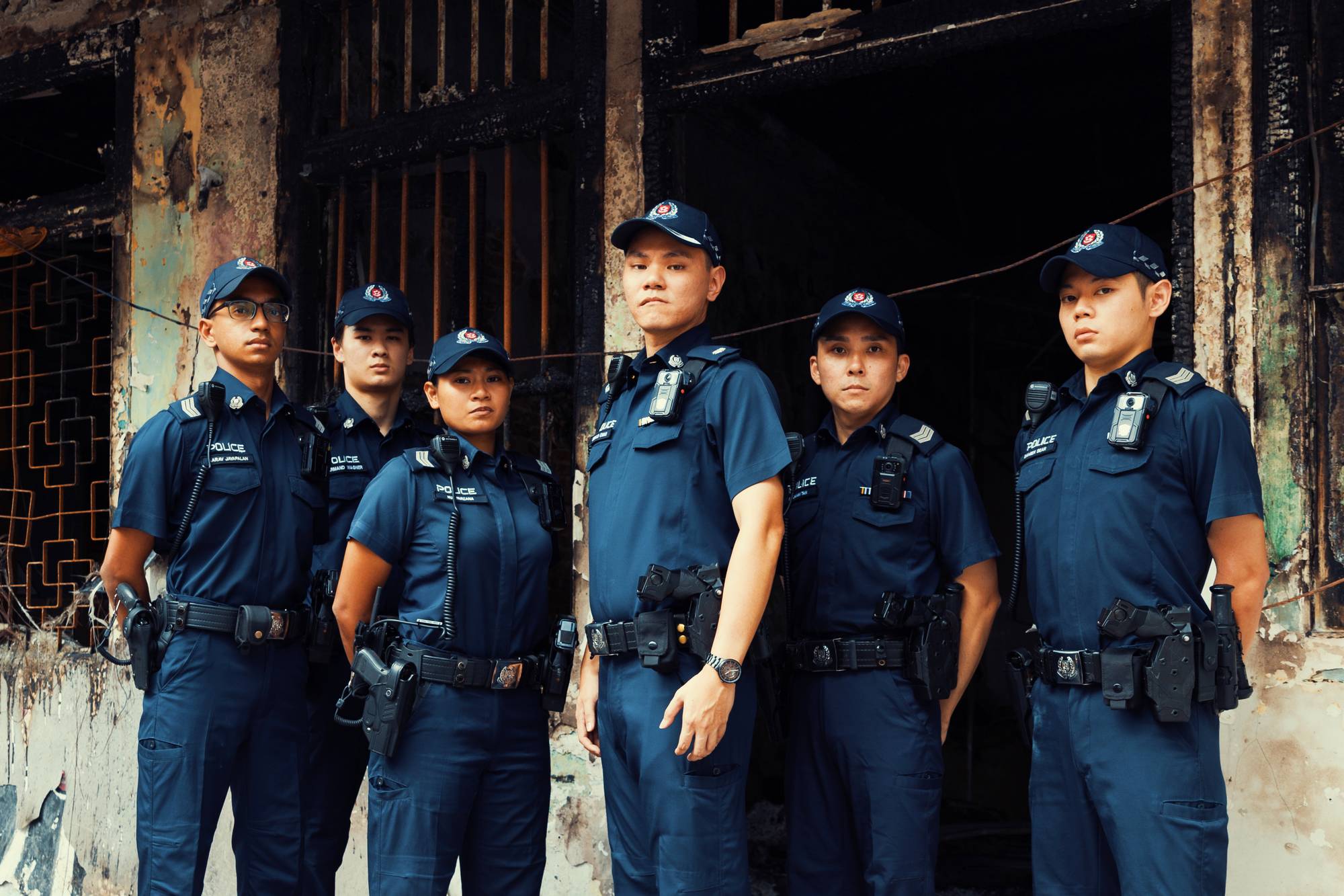 photo of 6 officers standing infront of a burnt unit that is completed charred and dark