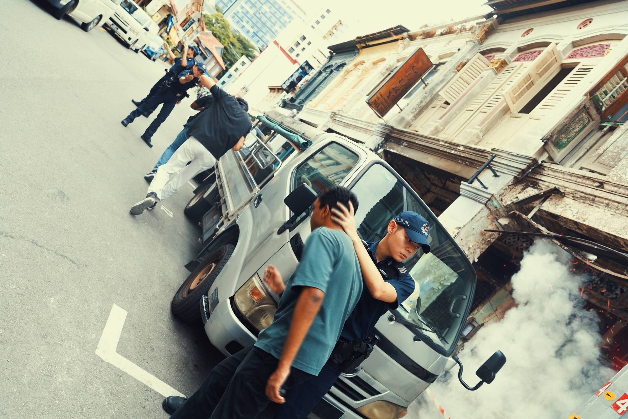 officers assisting to evacuate people away from the unit, ducking their heads and moving them along the road away 