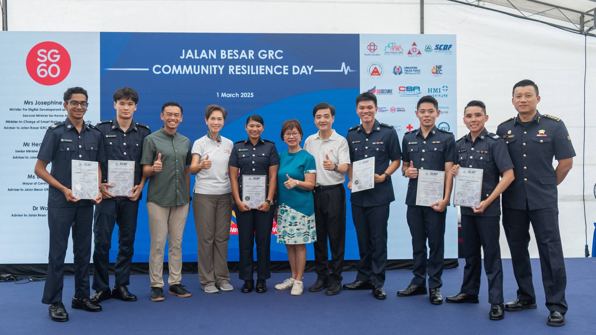 the officers receive the award on a stage at a community centre setting, with a white canopy tentage above them