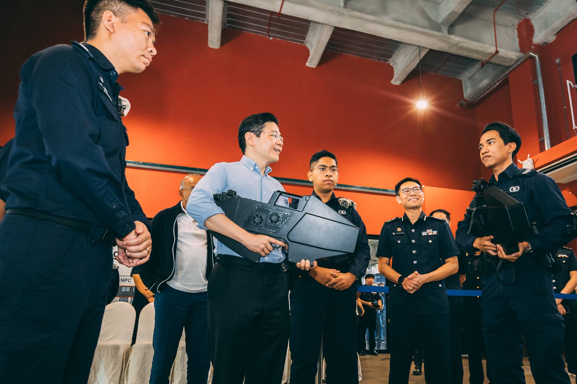 prime minister lawrence wong holding a jammer gun and talking to one of the pnsf