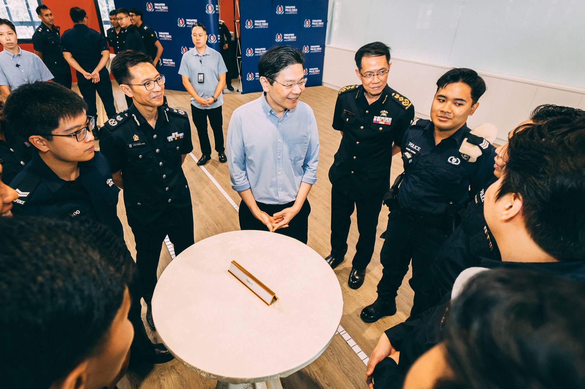 PM lawrence wong with other NS officers around a cocktail table, mingling and talking