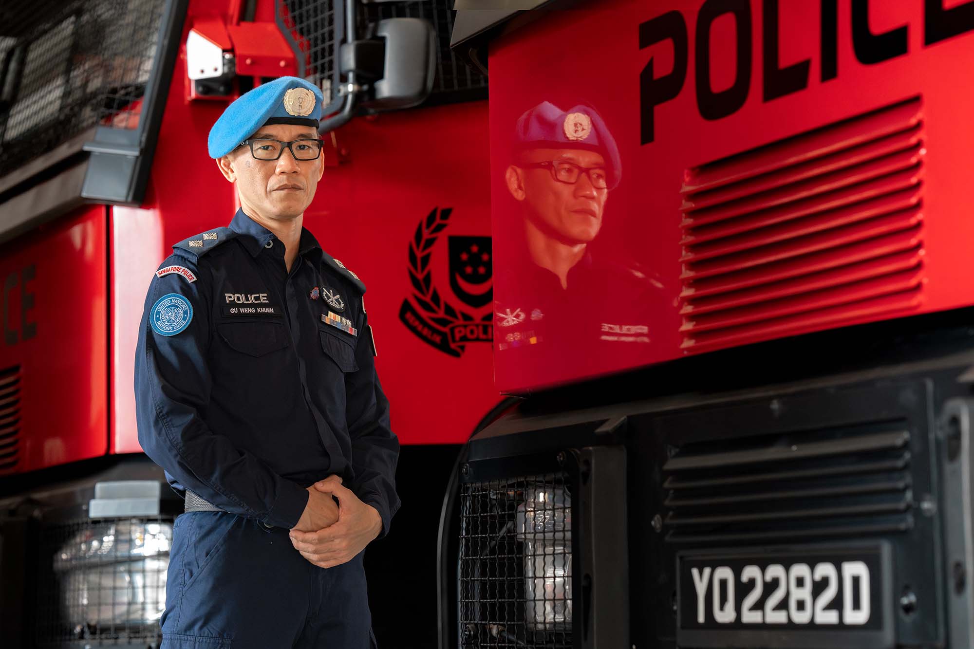 Insp Gu standing infront of the soc vehicle with his arms folder