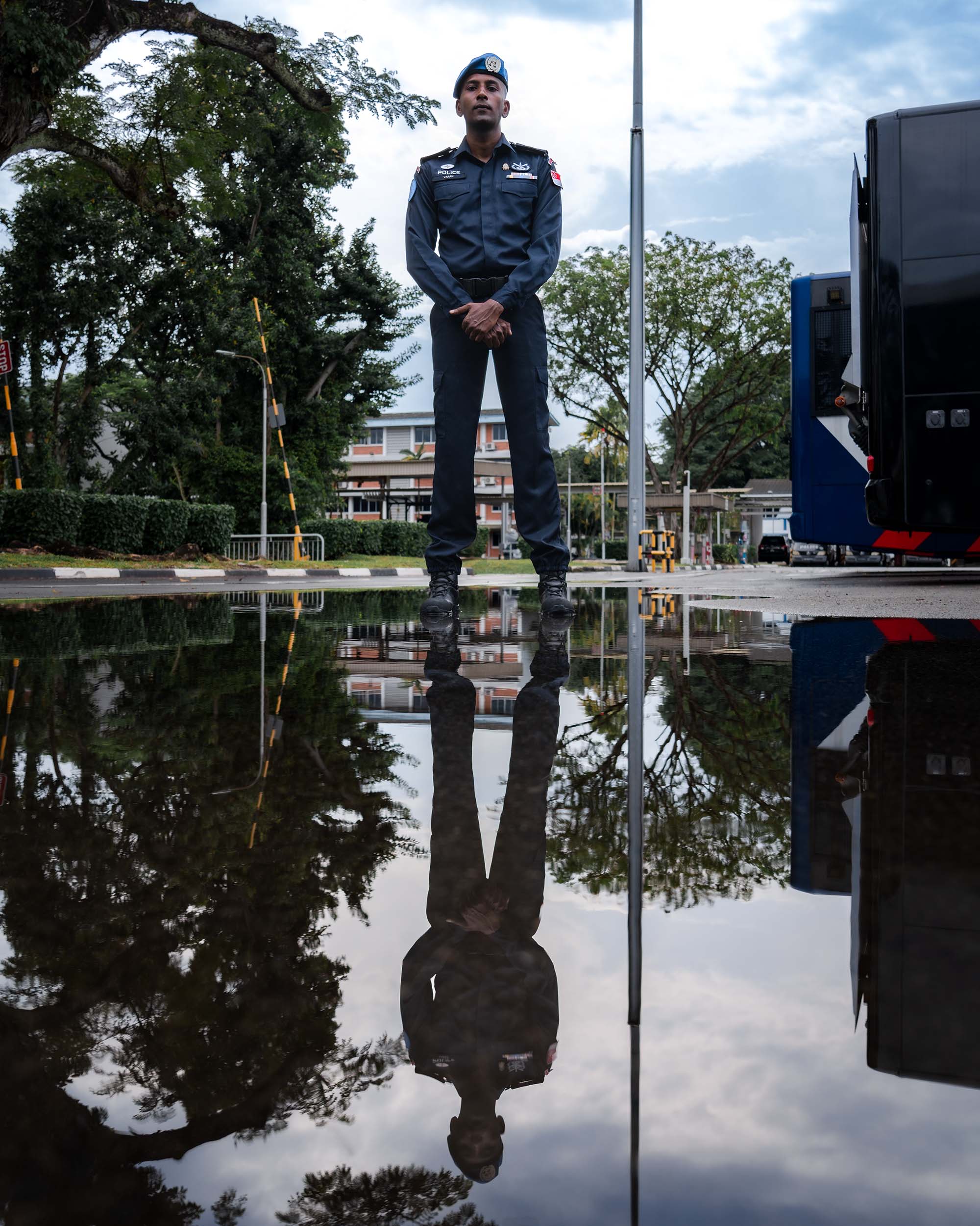 SI Varan standing infront of a water puddle, with his reflection being seen