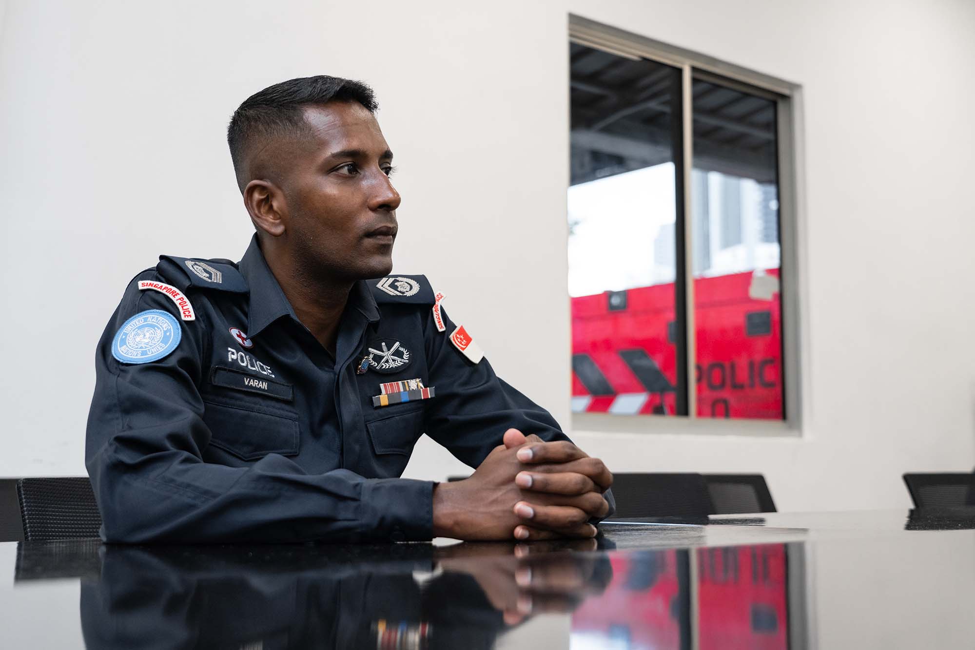 SI Varan seated on a chair in a meeting room, looking towards the 3pm direction