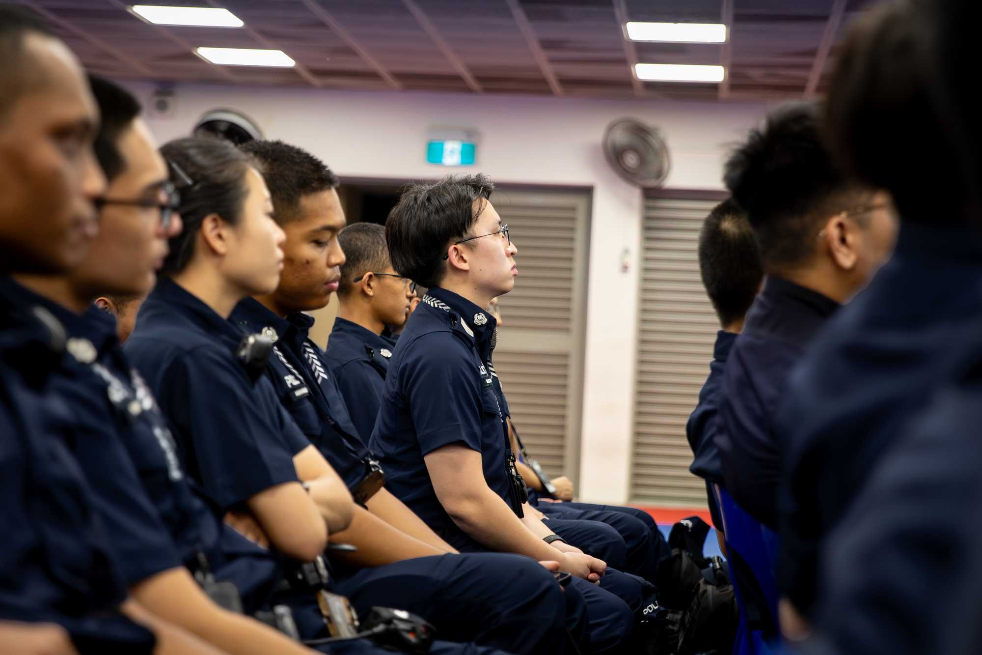 a photo from the side row of chairs, showing officers seated with Sgt Marc slightly leaning forward