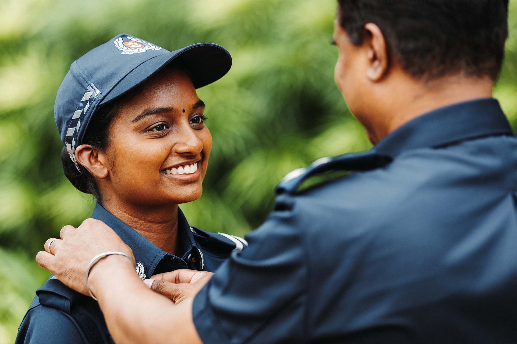a photo of the supt gunalan, photographed from the back, resting his hand on tharani's shoulder 