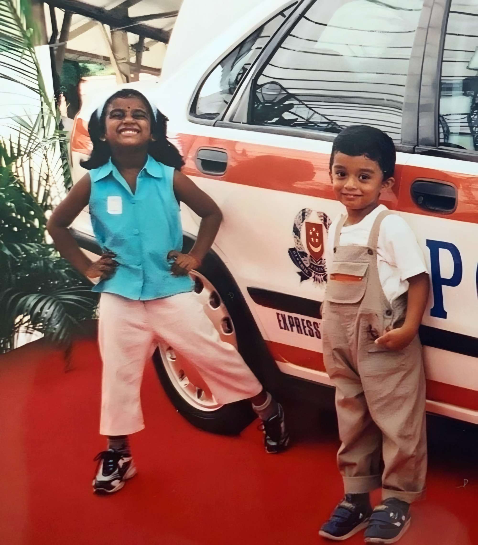 an old photo of tharani and her brother standing beside a TP Expressway Patrol Car