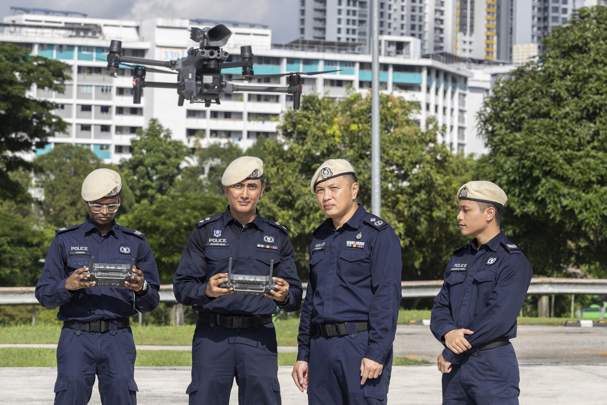 officers in blue uniform and beige berets operating a police drone