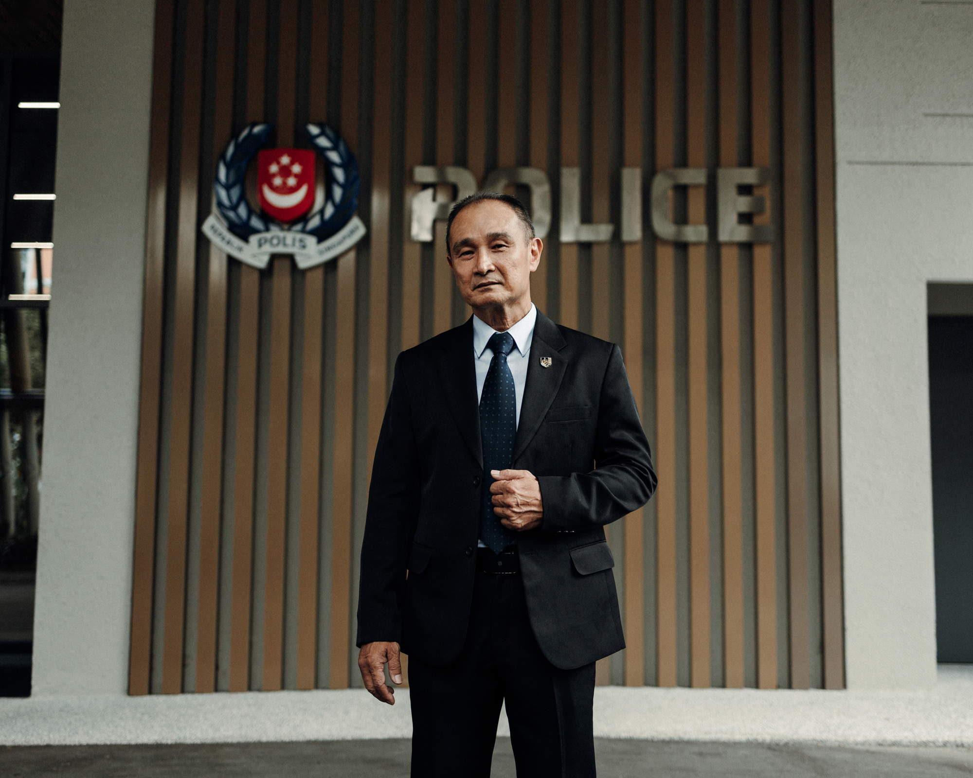 officer in suit and tie standing infront of a police signage at the seccom's new base