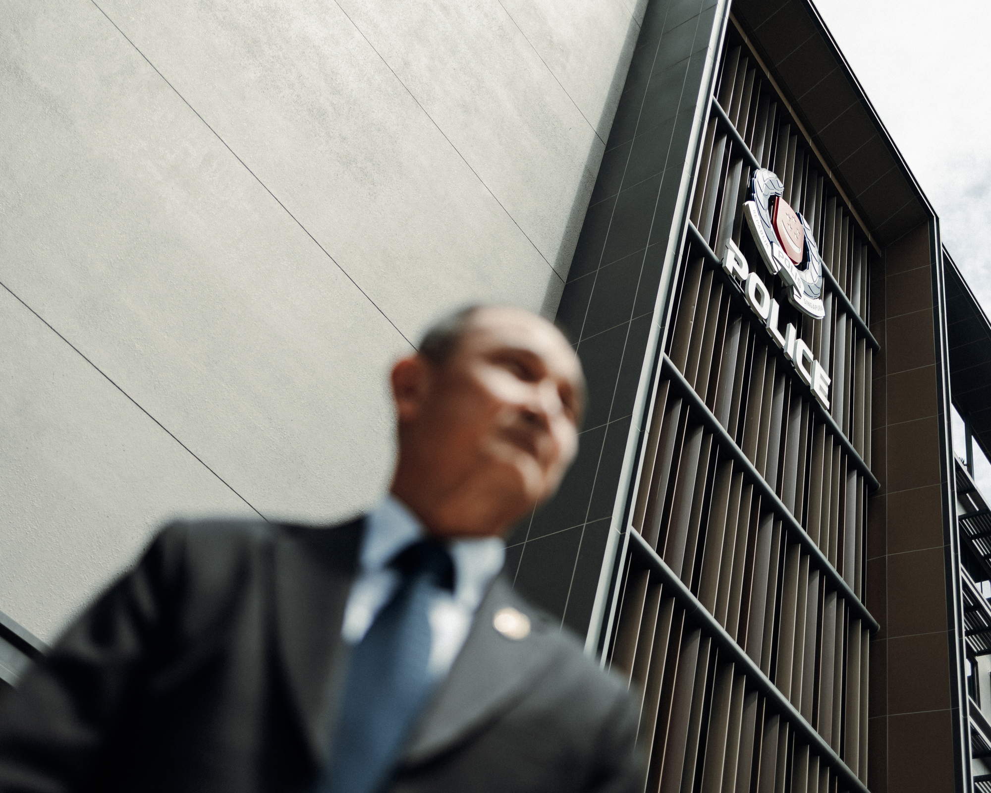 a bottom up shot of the officer in suit and tie but blurred, while the background of the police logo is focused