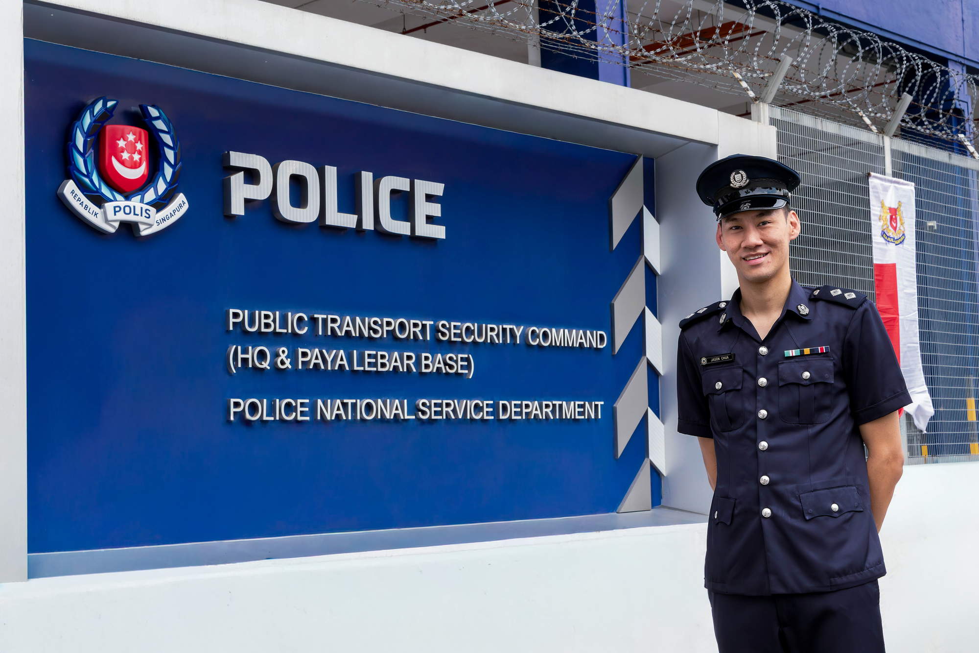 jason in uniform and peak cap standing beside the police signage at the TransCom building