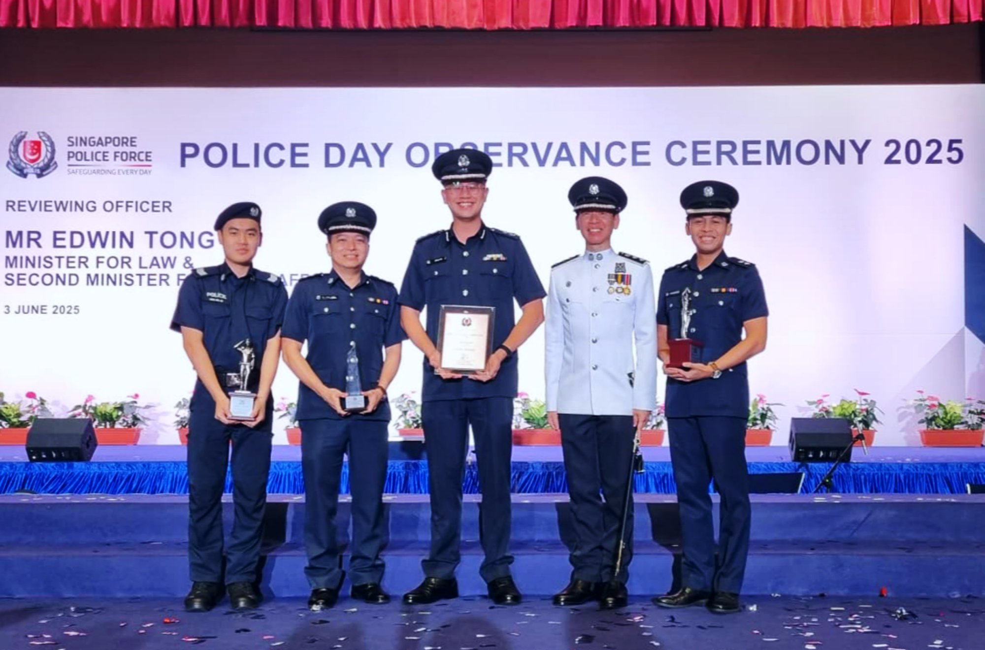 A group photo of Alastor and other Jurong Division award recipients during the Police Day Observance Ceremony 2025 in May. They are standing on the stage, with Commander Jurong in the middle. There's 5 people.