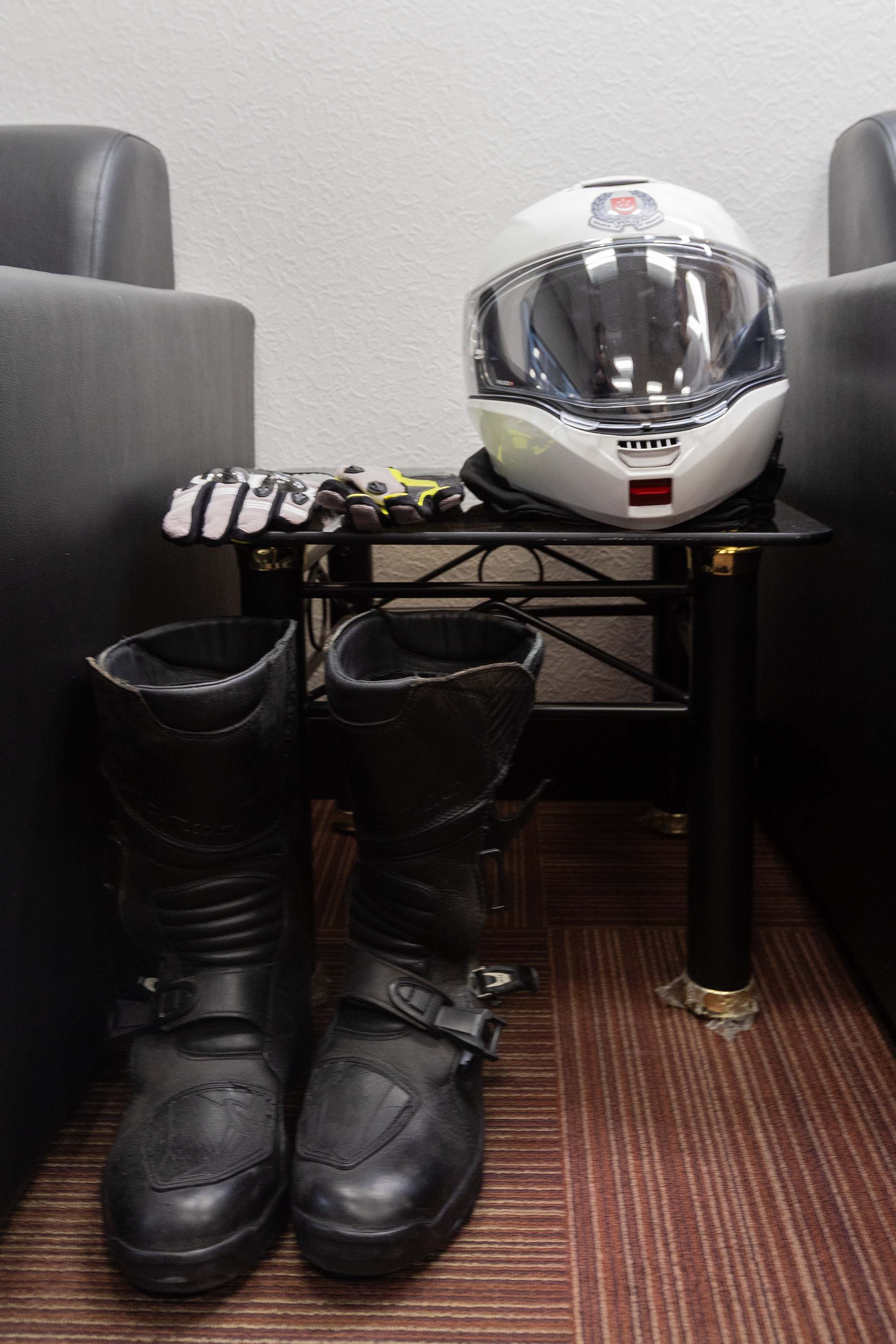 A shot of riding boots, gloves and a TP helmet placed on a coffee table beside a sofa