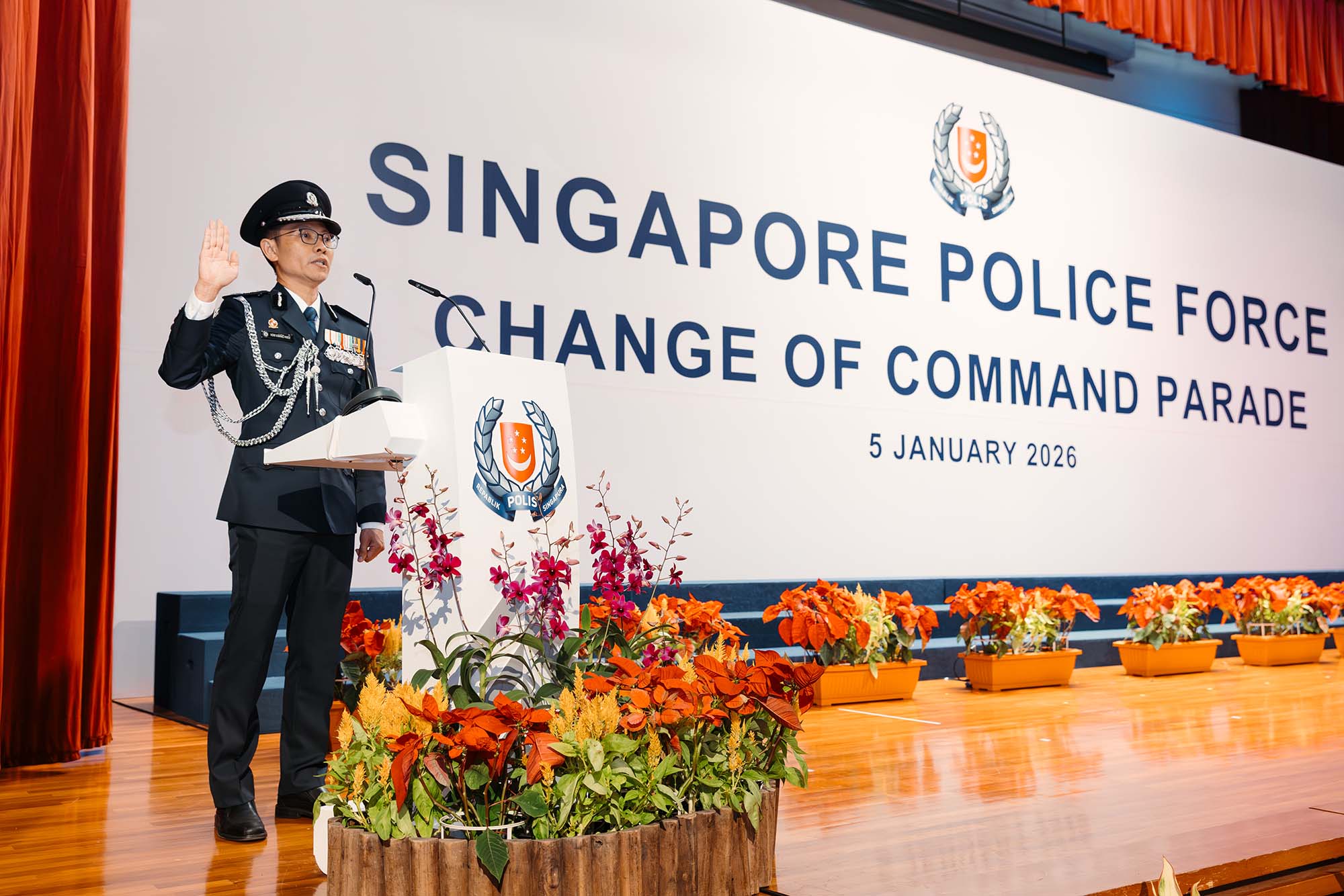 CP How Kwang Hwee in ceremonial blue uniform standing at the rostrum infront of backdrop on stage, with his right hand raised while he is reciting the oath.