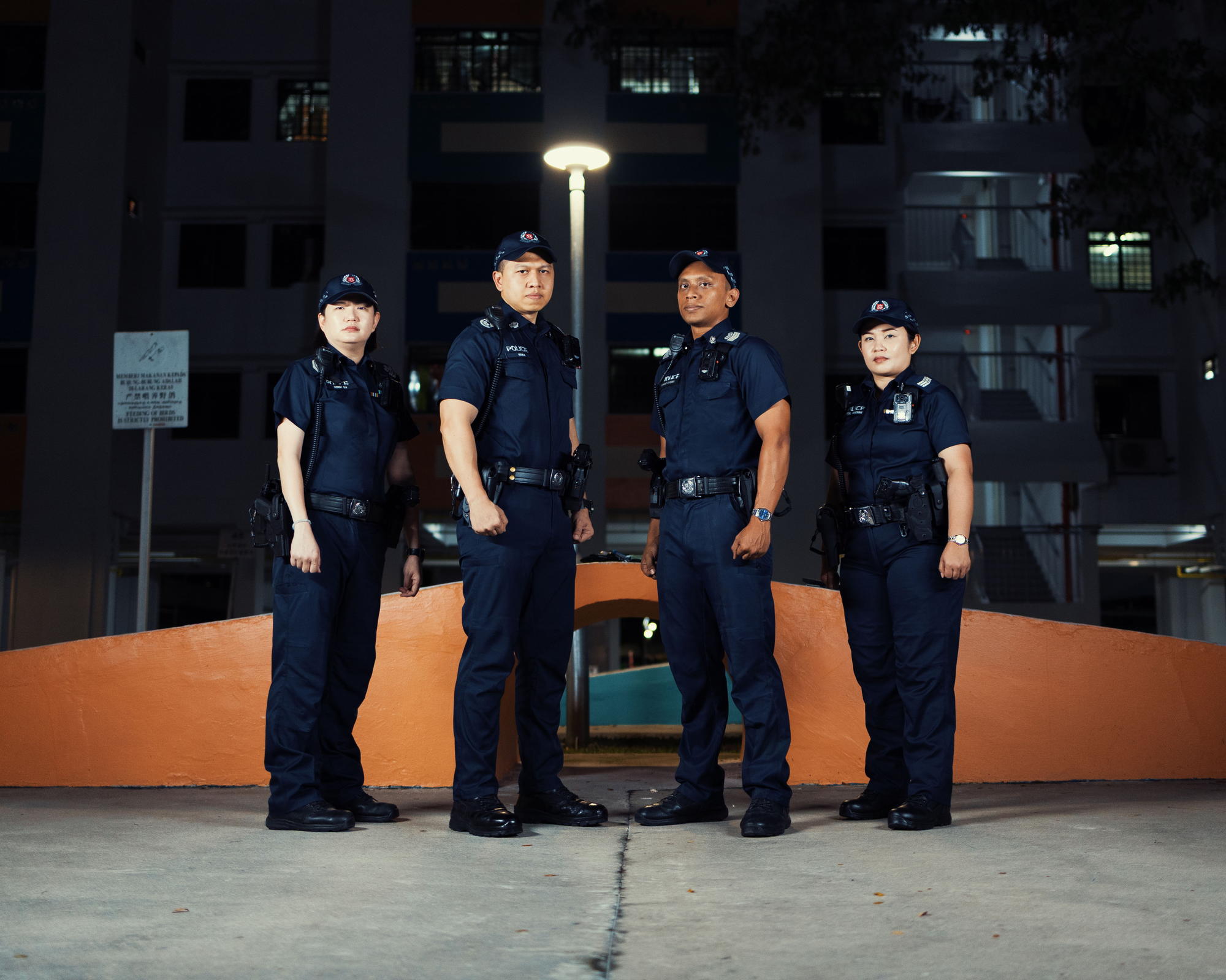 four officers posing towards the camera, standing together in the middle of an open area between two blocks. 