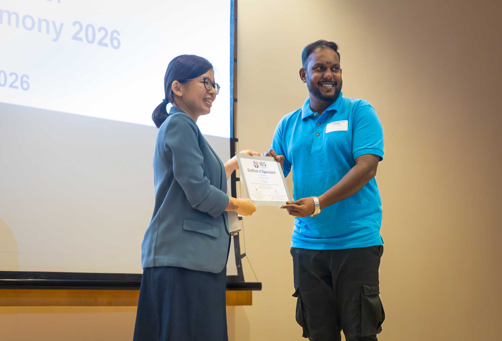 A migrant worker receives his certificate on stage. 