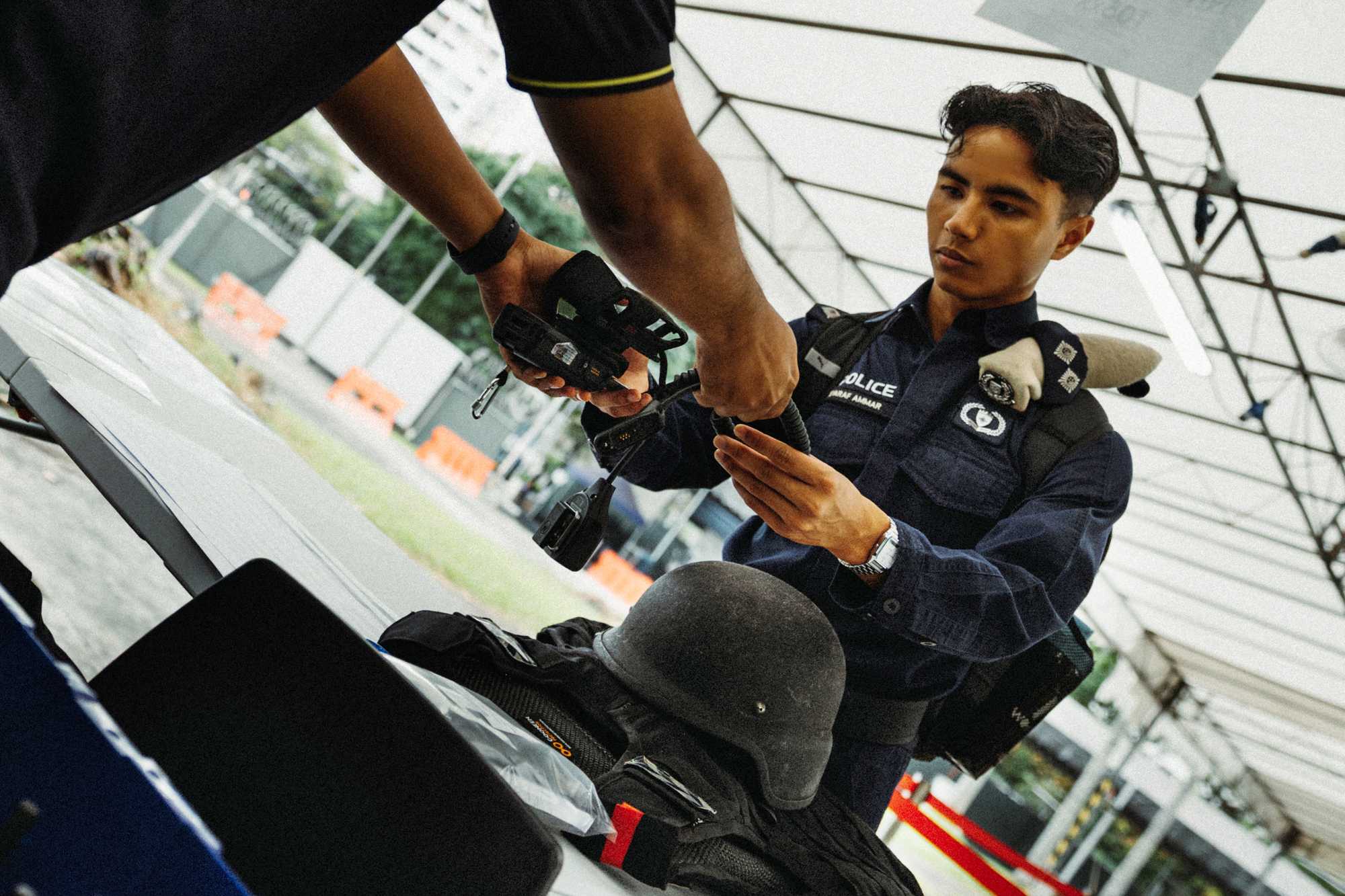 an officer in uniform collecting his operation gear, with his helmet seen on the table