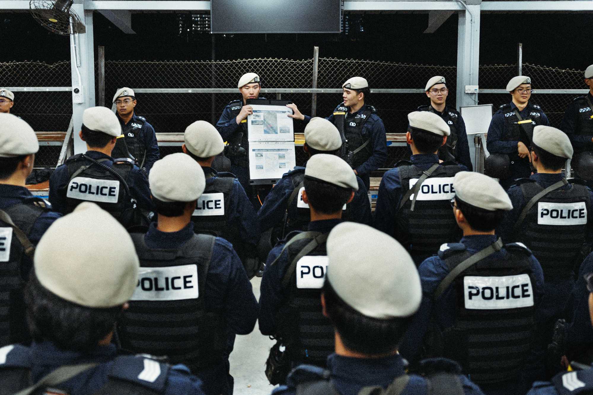 officers sporting their beret and full operation gear facing forward to a group of officers holding a piece of paper and briefing them